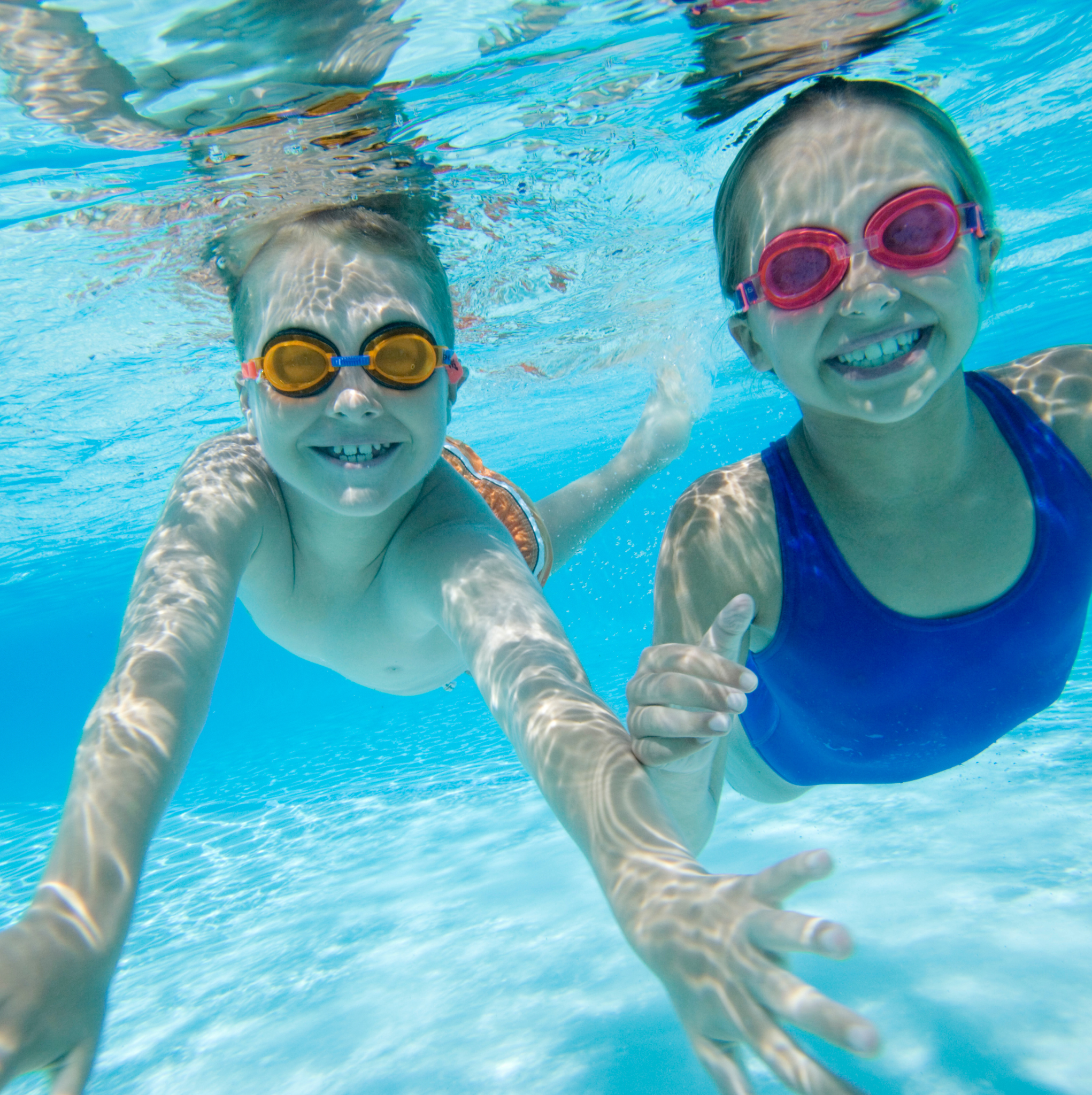 Two girls smiling underwater in a swimming pool