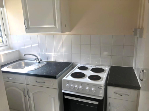 Small kitchen with white ubits, sink and cooker.