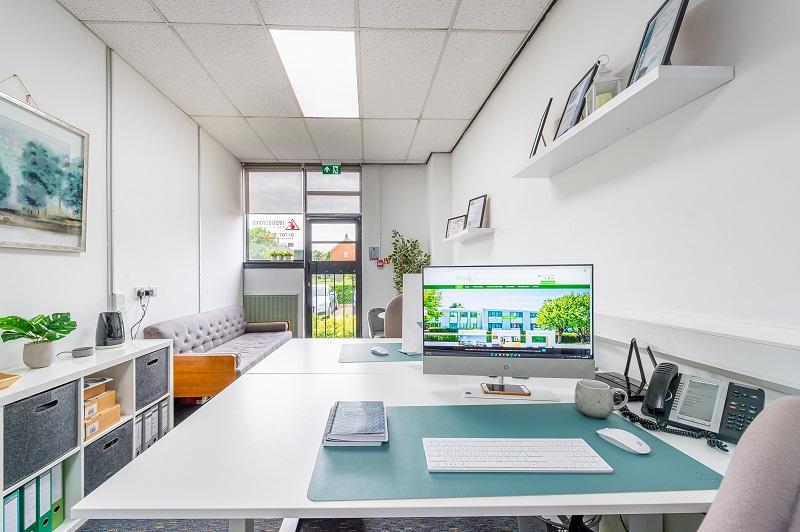 Inside of a WelTech room where there is a desk, monitor, mouse and keyboard with a sofa in the background.