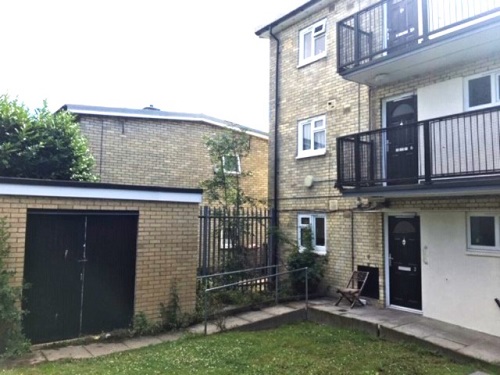 Three storey flats with balconies and grass area in front.