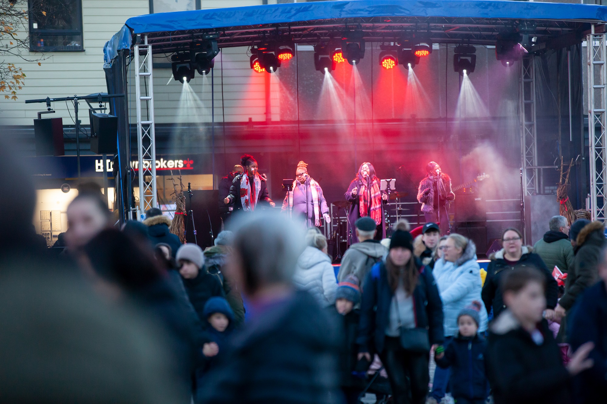 People stood in Hatfield town centre facing a stage with women singing on it