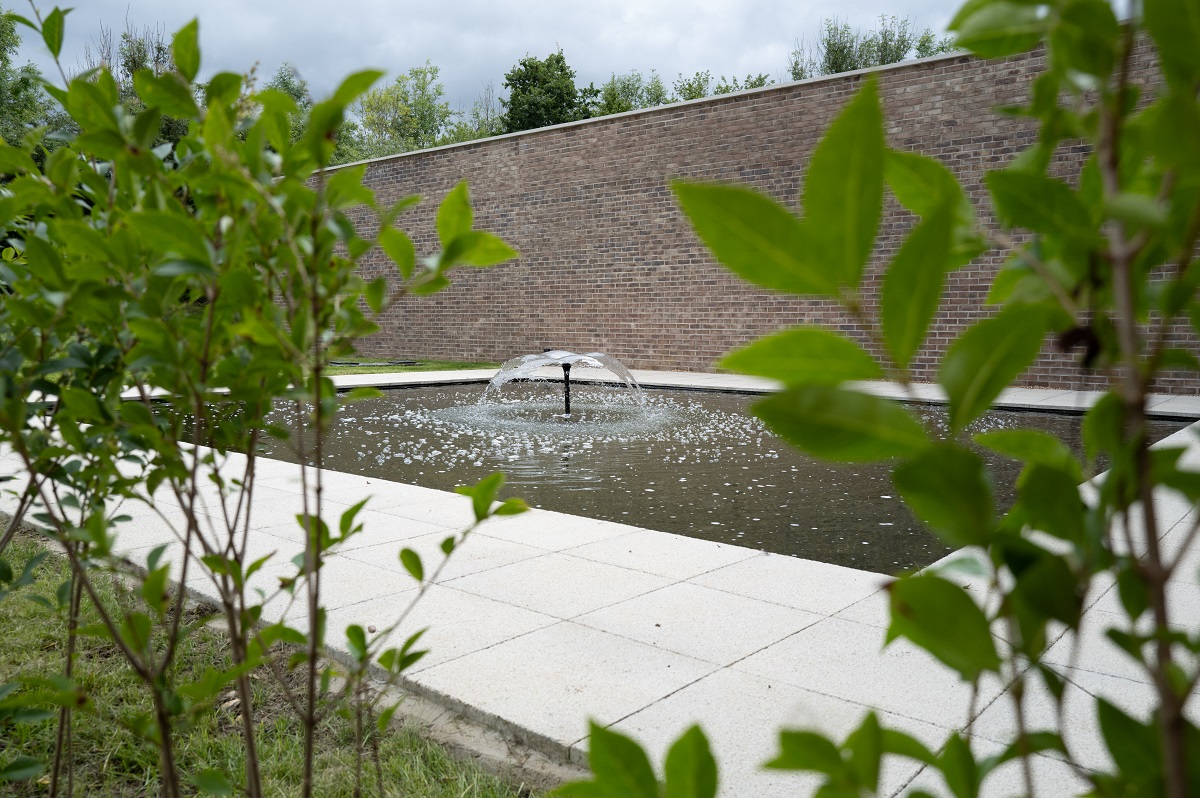 Pond with a fountain in the middle of it, with plants on either side