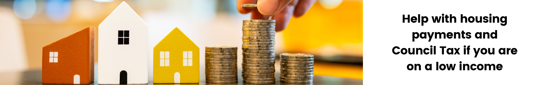 Image of wooden toy houses next to a stack of coins